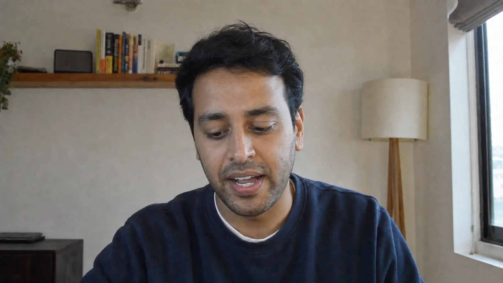 A man on a video call reading notes below his camera, eyes looking down